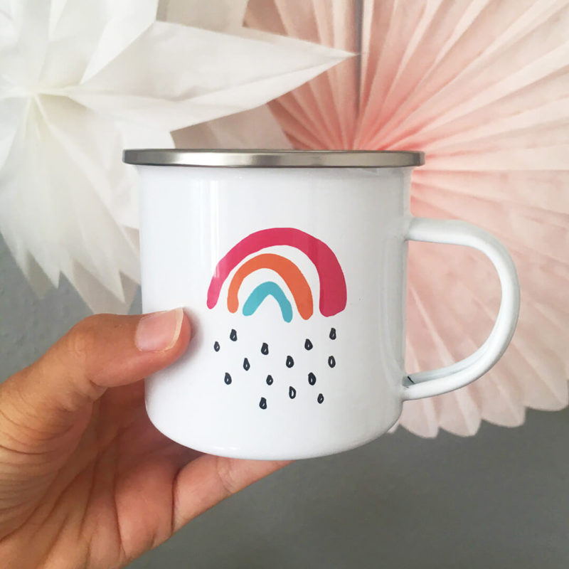 Sarah hält die Emaille-Tasse Kleiner Regenbogen in der Hand