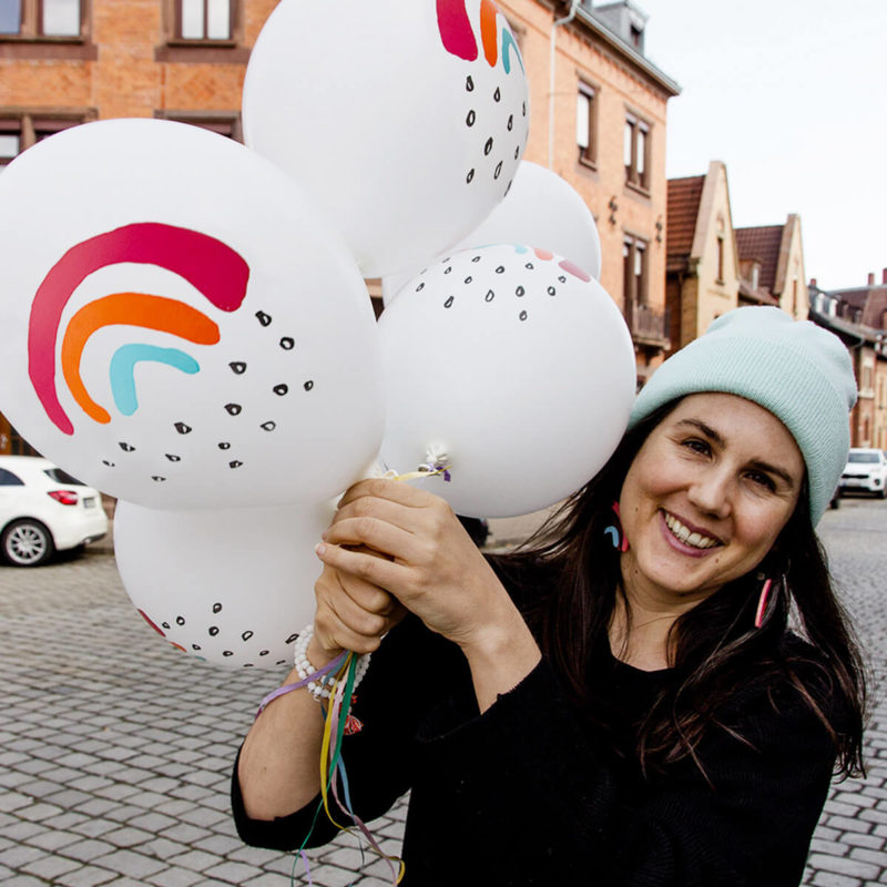 Sarah hat die Luftballons mit dem Motiv Kleiner Regenbogen in der Hand