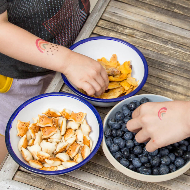 Kinder beim Snacken mit Regenbogen Tattoos auf dem Arm