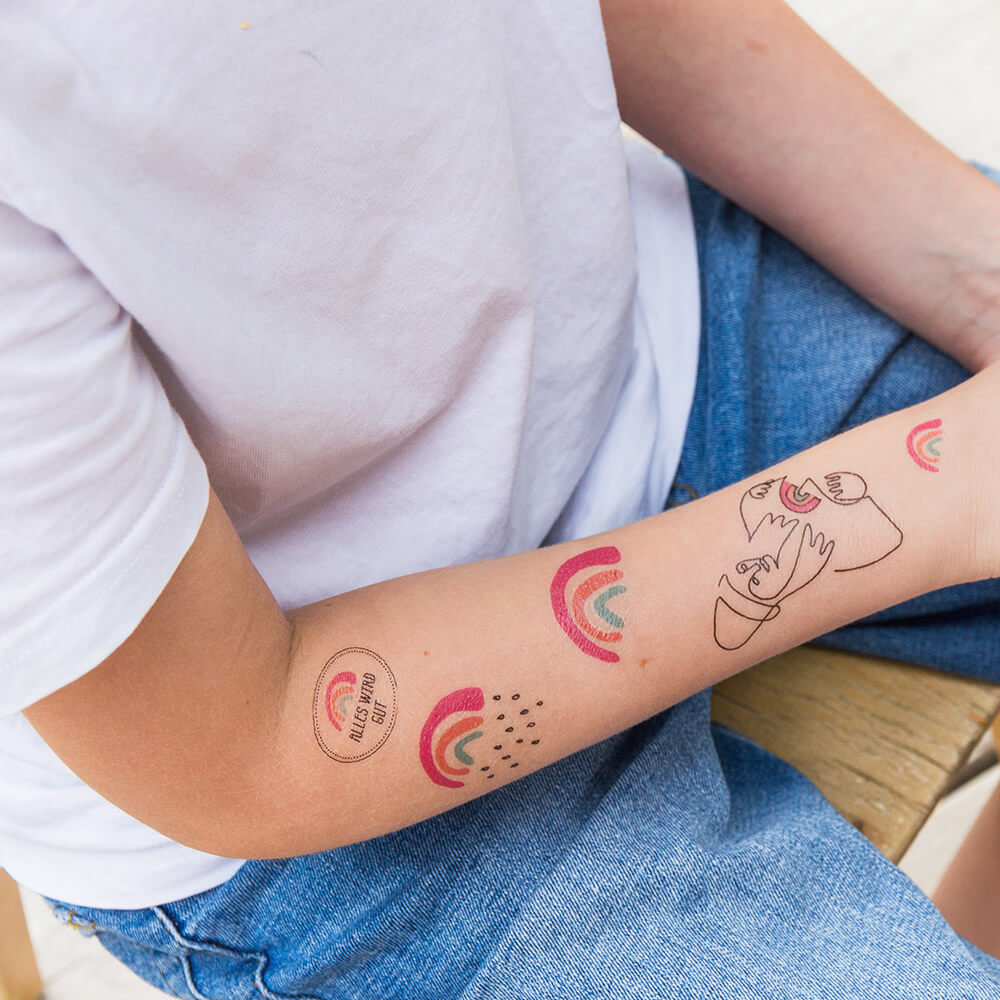 Junge mit vielen unterschiedlichen Kleiner Regenbogen Klebetattoos auf dem Arm