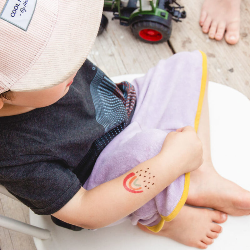 Kleiner Regenbogen als Klebetattoo auf einem Kinderarm