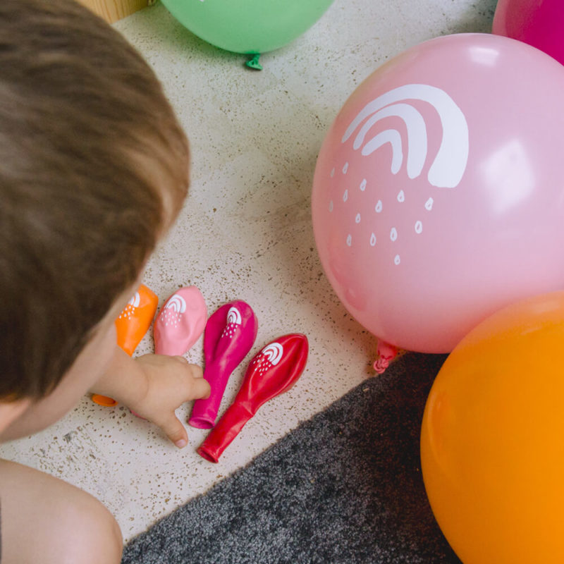 Ein kleiner Junge spielt mit den Luftballons Kleiner Regenbogen